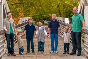 Cramer Imaging's professionally photographed portrait of a family holding hands on a bridge with fall leaves in Idaho Falls, Bonneville, Idaho