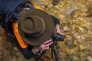 Photograph of landscape photographer Audrey Cramer shooting a photo down in a flowing stream of water