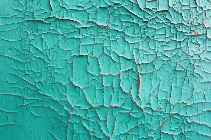 Close-up photo of teal-colored paint alligatoring and flaking off