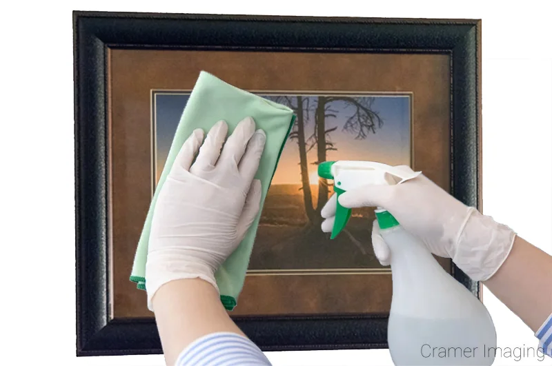 Photo of a person cleaning the glass surface of a framed photograph by Audrey Cramer Photography