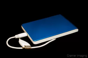 Stock photograph of a blue and white USB external hard drive disk on a black background