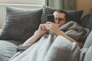 Photograph of a lazy person relaxing on a comfy couch while on a cell phone