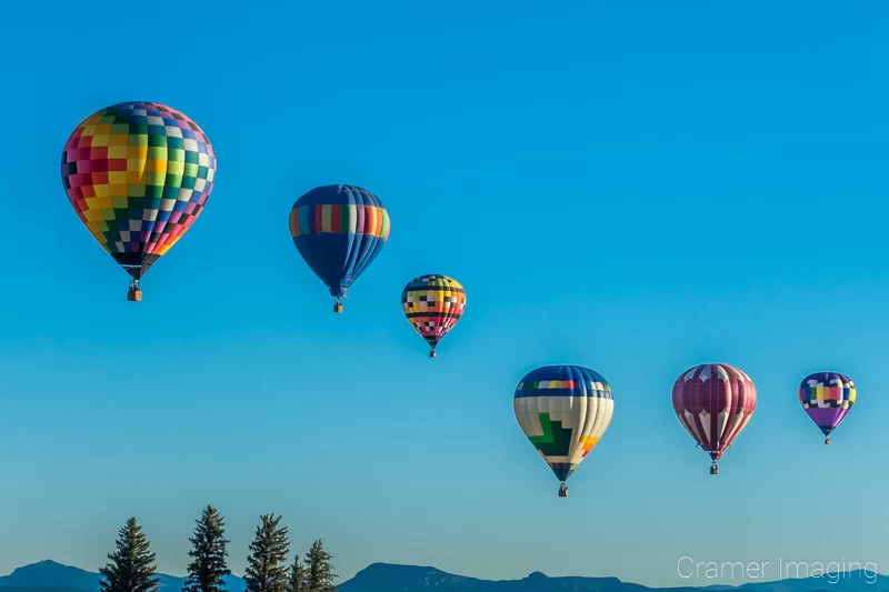 Audrey Cramer Photography's fine art photograph of six hot air balloons in a reverse s shape drifting over the Panguitch Utah landscape