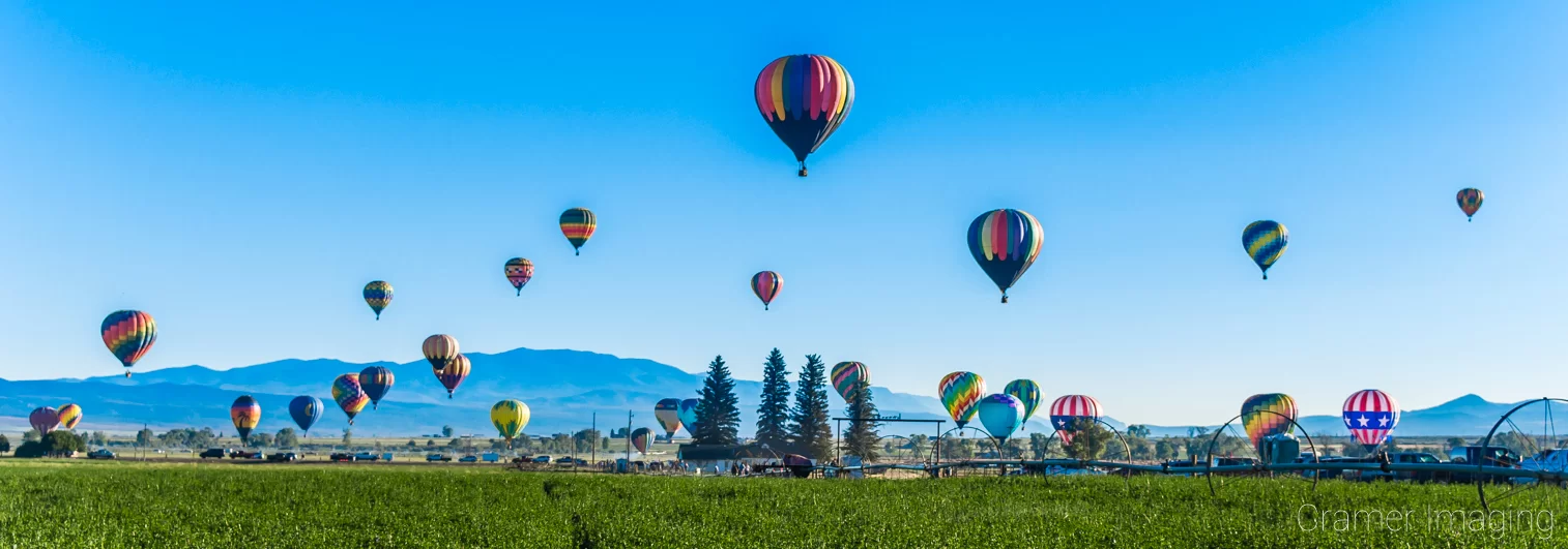 Cramer Imaging's fine art landscape panorama photograph of several hot air balloons in flight forming a bell curve over Panguitch Utah