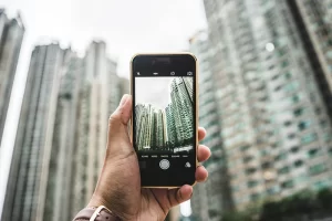 Photograph of a man taking a cell phone photo of buildings