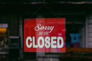 Photograph of a window with a red "Sorry we are closed" sign hanging in it