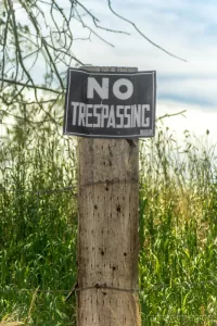 Cramer Imaging's photograph of an old "no trespassing" sign on a fence post with grass