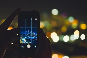 Photograph of a person taking a cell phone picture of city lights at night with rule of thirds grid lines visible