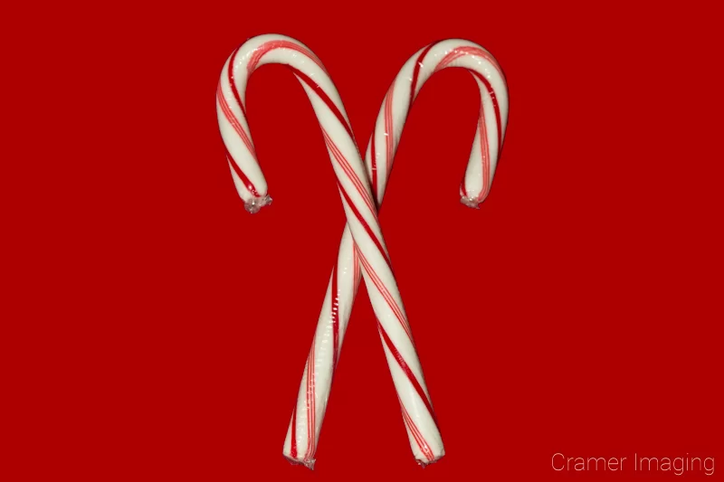 Audrey Cramer Photography's professional quality holiday or Christmas product photograph of two crossed candy canes on a red background