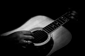 Cramer Imaging's professional quality fine art music low key black and white photograph of hands strumming an acoustic guitar