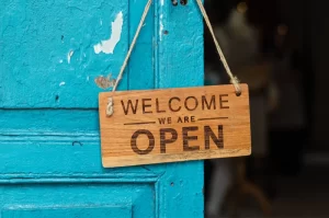 Photograph of a welcome we are open sign on a blue door