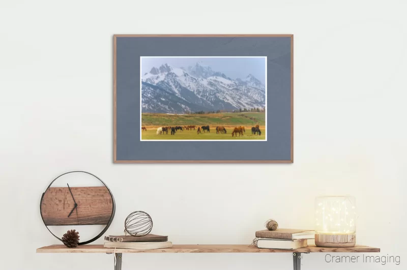 Photograph of a room containing a shelf with rustic decorations and a framed copy of Audrey Cramer Photography's "Tetons and Horses" landscape photo