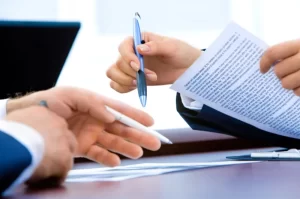 Photo of a man and woman holding pens and comparing notes in a business setting