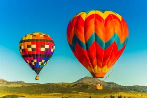 Fine art landscape photograph of 2 hot air balloons flying against a mountain backdrop in Panguitch, Utah by Cramer Imaging