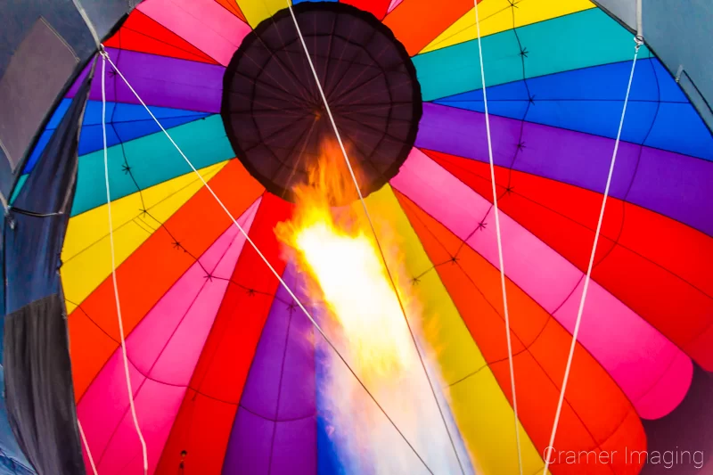 Fine art photograph of a flaming jet shooting up a colorful hot air balloon in Panguitch, Utah by Audrey Cramer Photography