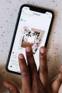 Photo of a hand browsing through Instagram on a smartphone