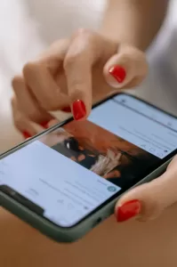 Photograph of a woman's handss browsing through Instagram on a smartphone