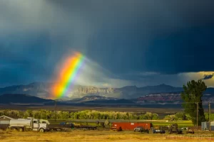 Cramer Imaging's fine art landscape photograph of a bright rainbow against moody storm clouds over a field in Panguitch, Utah