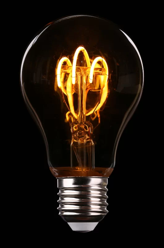 Photograph of a glowing clear light bulb on a black background