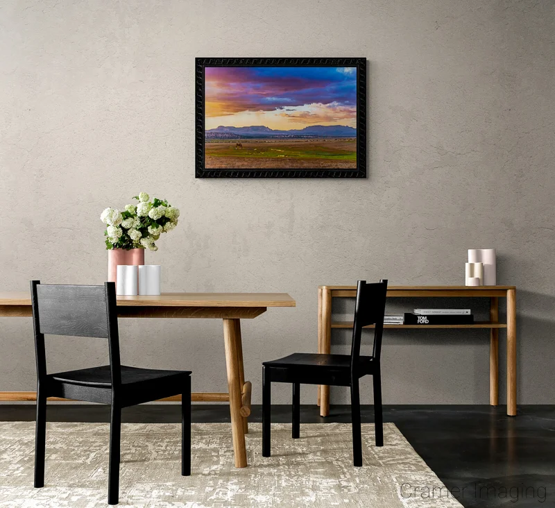 Photograph of a neutral dining area with a Audrey Cramer Photography's "Open Range" on the wall and white flowers