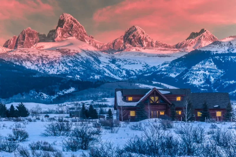 Audrey Cramer Photography's professional quality landscape photograph of the Teton mountains and a cabin at sunset during winter