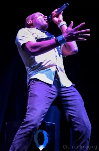 Cramer Imaging's professional quality concert photograph of Alex Boyé in scout uniform standing and singing in Firth, Idaho