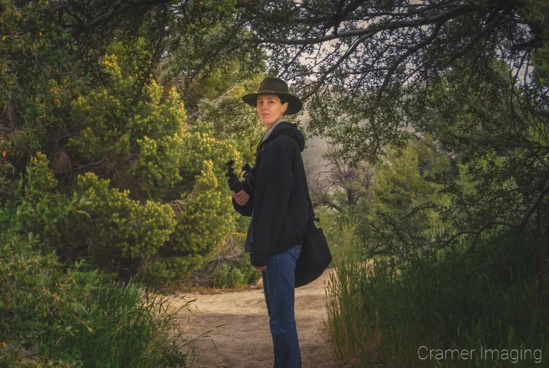 Behind-the-scenes photograph of landscape photographer Audrey Cramer looking back up the trail