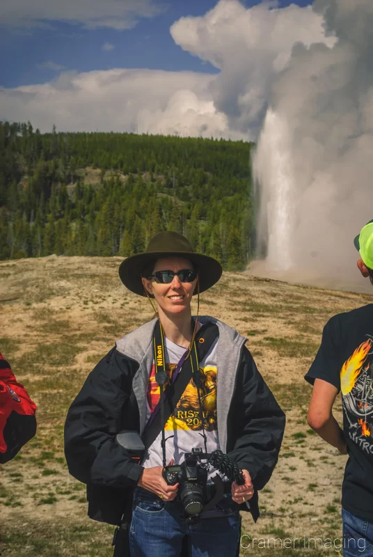 Professional landscape photographer Audrey Cramer standing in a crowd at Old faithful as the geyser erupts