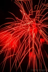 Badly-taken and timed photograph of a red firework exploding in the sky