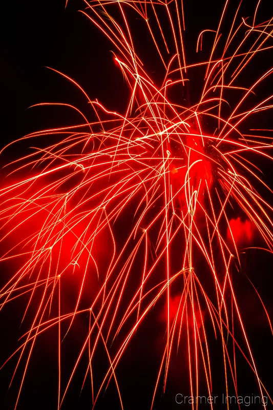 Badly-taken and timed photograph of a red firework exploding in the sky