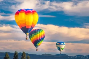 Cramer Imaging's fine art photograph of three hot air balloons taking flight in Panguitch Utah over a trees and mountains