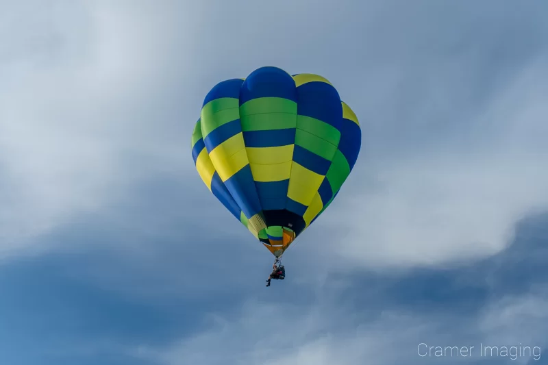 Audrey Cramer Photography's fine art photograph of one single-passenger hot air balloon taking flight in Panguitch Utah with a blue partly cloudy sky