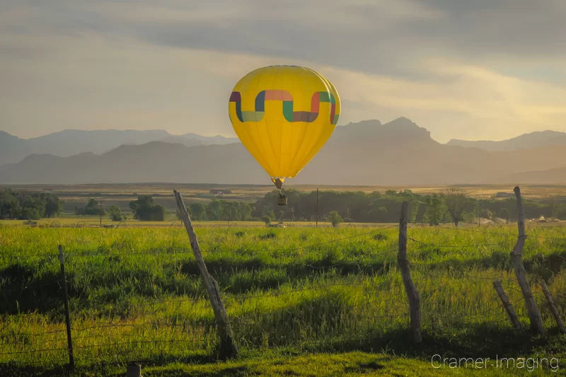 Audrey Cramer Photography's fine art photograph of one yellow rainbow hot air balloon taking flight in Panguitch Utah over a field