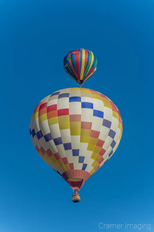 Audrey Cramer Photography's fine art photograph of two colorful hot air balloons taking flight in Panguitch Utah with a blue morning sky