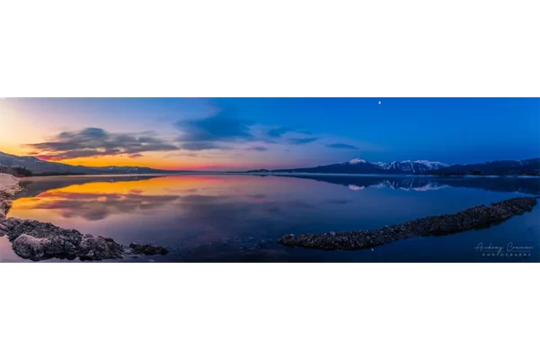 Cramer Imaging's professional quality landscape panorama photograph of the sky and moon reflecting in Henry's Lake at dawn with blue and golden hours