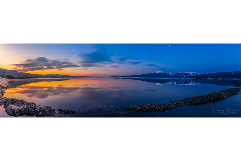 Cramer Imaging's professional quality landscape panorama photograph of the sky and moon reflecting in Henry's Lake at dawn with blue and golden hours