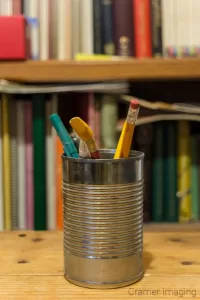 Cramer Imaging's photograph of a can with pencils and a bookshelf demonstrating bokeh