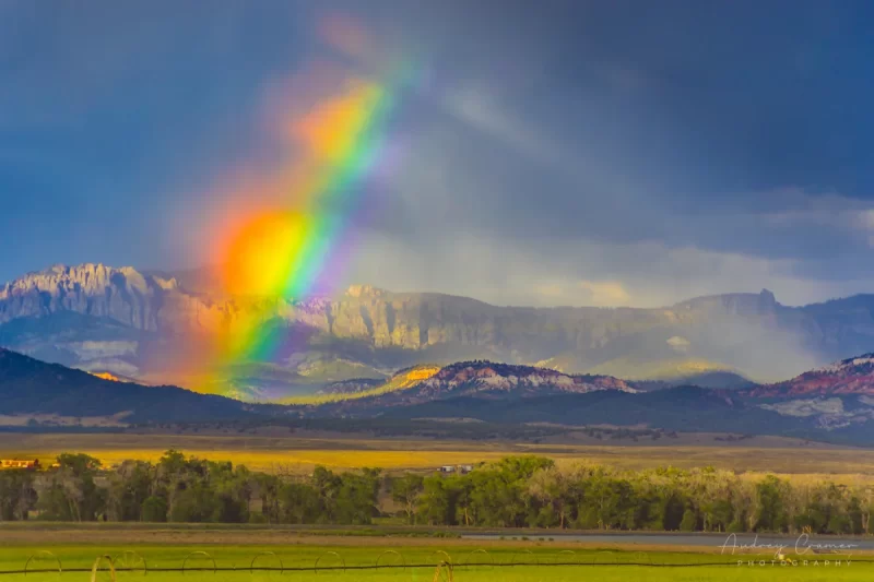 Cramer Imaging's fine art landscape photograph of a broken rainbow with light streaks against moody storm clouds over a field in Panguitch, Utah