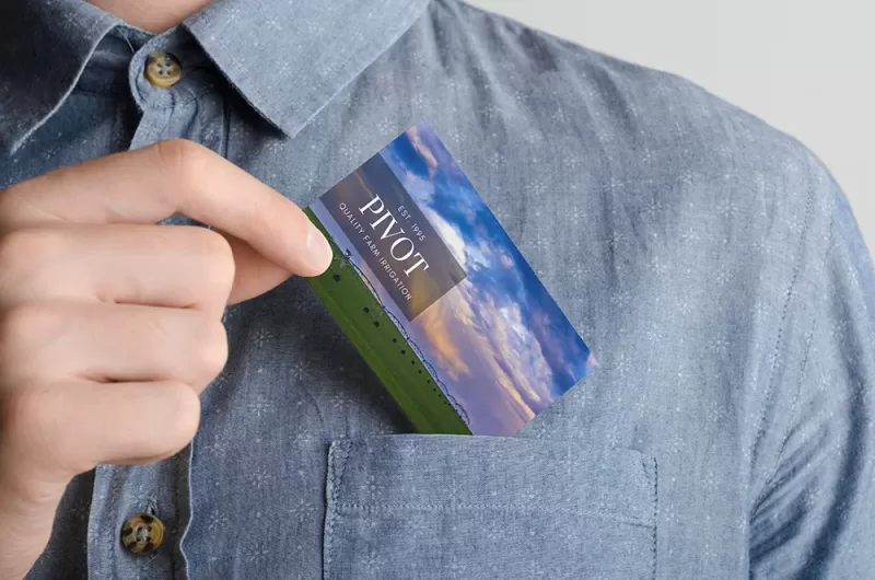 Mockup of a business card featuring Audrey Cramer Photography landscape photography being placed into the shirt pocket of a man's shirt