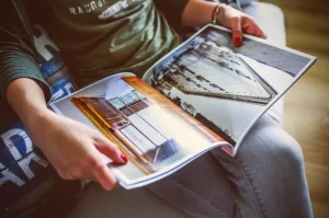 Photograph of a person seated and looking at a printed catalog