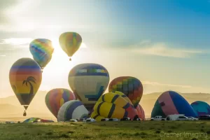 Cramer Imaging's fine art photograph of a hot air balloon cluster taking flight in Panguitch Utah with a sunburst between 2 aerial balloons