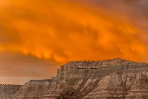 Cramer Imaging's fine art landscape photograph of fiery orange fireball in the clouds above the mountains of Cannonville Utah