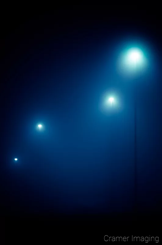 Audrey Cramer Photography's professional quality fine art photograph of four blue-toned streetlights in the dark and fog of Pocatello, Bannock, Idaho