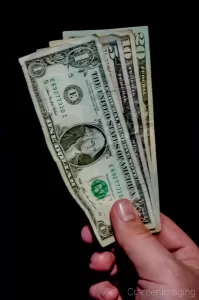 Cramer Imaging's professional quality photograph of a hand holding a one, five, ten, and twenty dollar bill