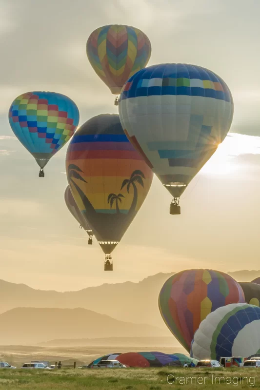 Audrey Cramer Photography's fine art photograph of a hot air balloon cluster taking flight in Panguitch Utah with a sunburst off 1 aerial balloon