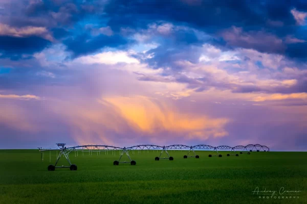 Audrey Cramer Photography's professional quality landscape photograph of a farm field and equipment with colorful clouds in Rexburg, Madison, Idaho