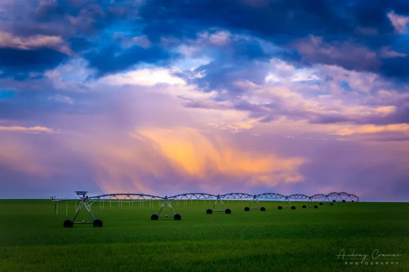 Cramer Imaging's professional quality landscape photograph of a farm field and equipment with colorful clouds in Rexburg, Madison, Idaho