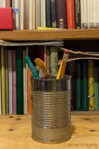 Cramer Imaging's photograph of a can with pencils and a bookshelf demonstrating no bokeh