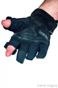 Photograph of a black photographer's glove with removable thumb and index finger sections on white background by Cramer Imaging