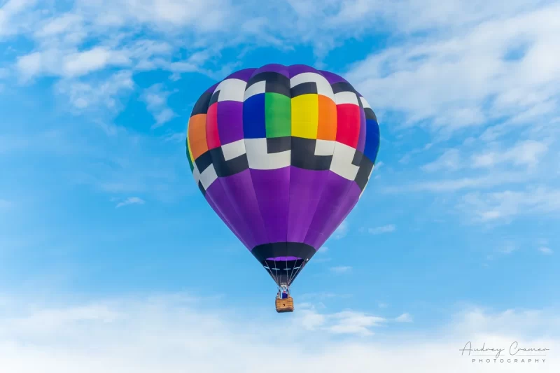 Audrey Cramer Photography's fine art photograph of one purple rainbow hot air balloon taking flight in Panguitch Utah with a blue partly cloudy sky